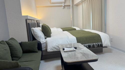 a bedroom with a bed and a couch and a table at attomi hostel 2 in Sapporo