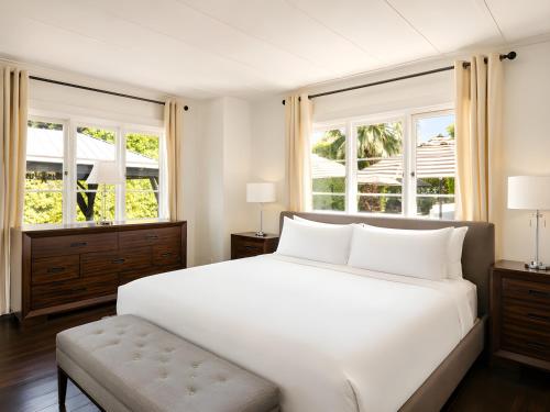 a bedroom with a white bed and two windows at Gloria Palm Springs in Palm Springs