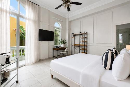 a white bedroom with a bed and a television at Hotel Magnolia Boutique in Panama City