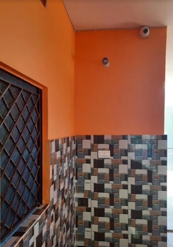 a bathroom with an orange wall and a mosaic tile wall at Chaukhamba hill homestay in Ukhimath