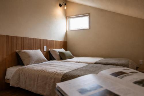 two beds in a hotel room with a window at mizuki natural villa Garden in Higashikawa