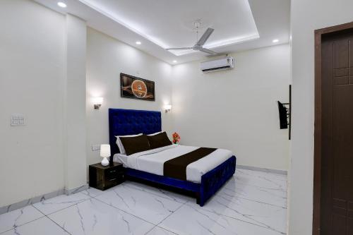 a bedroom with a bed with a blue head board at Super Hotel O Clock Tower Dehradun Formerly Dooncity Suites in Dehradun