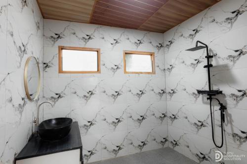 a bathroom with white marble walls and a black sink at Umacabana 2 in Diyeng