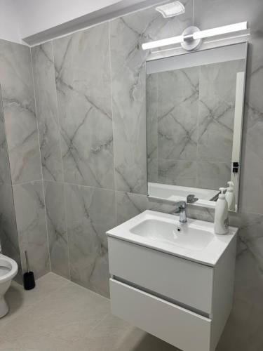 a white bathroom with a sink and a mirror at Apartament Magnolia Panoramic in Craiova