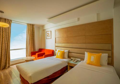 a hotel room with two beds and an orange chair at Bloom Boutique Bangalore Palace Rd in Bangalore