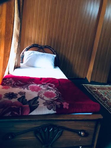 a bed with a red blanket and a white pillow at Rama lake view Hotel in Astor
