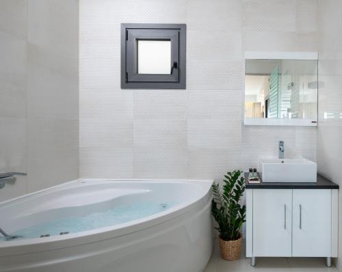 a white bathroom with a tub and a sink at Suite Home in Anthoúsa