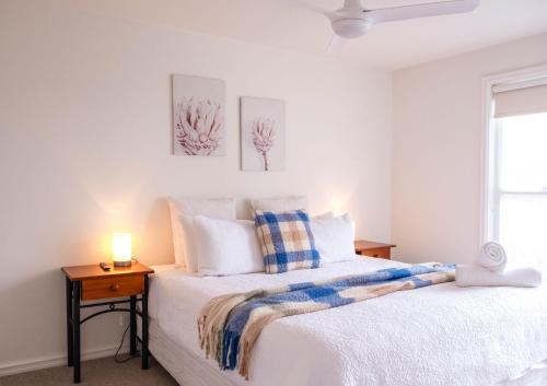 a white bedroom with a bed and a night stand at Moyne Views 2 in Port Fairy