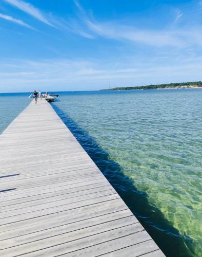 a person walking on a wooden pier over the water at RYMLIG RENOVERAD GÄSTBOSTAD med egen ingång nära stranden i HÄLLEVIK in Sölvesborg