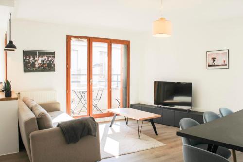 a living room with a couch and a tv and a table at Large apartment with balcony - Stade de France in Saint-Denis