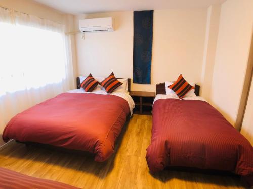 two beds sitting next to each other in a room at Nagoya Minpaku, KANAYAMA BASE in Mutsunochō