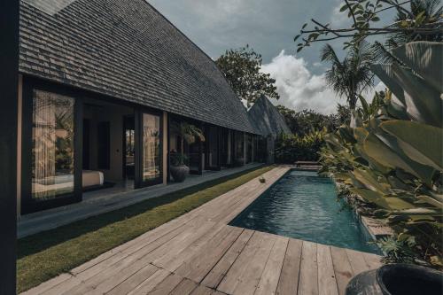 a swimming pool next to a house with a wooden deck at MIZU Boutique Villas - Unique stay in Uluwatu in Uluwatu