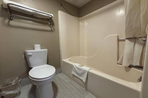 a bathroom with a toilet and a bath tub at Super 8 by Wyndham Normal Bloomington in Bloomington