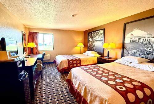 a hotel room with two beds and a desk at Super 8 by Wyndham Melrose in Melrose