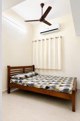 a bedroom with a bed with a ceiling fan at Eden Cozy Villa in Virāmpattinam