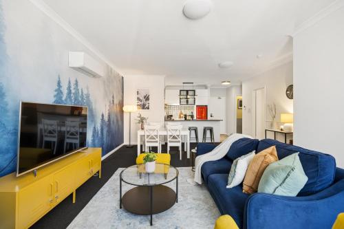 a living room with a blue couch and a tv at OPTUS Stadium 2BR CBD Apartment with FREE Parking in Perth
