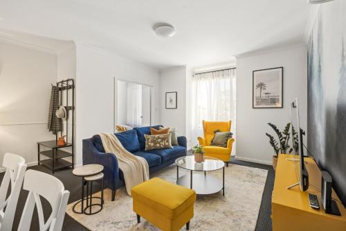 a living room with a blue couch and yellow chairs at OPTUS Stadium 2BR CBD Apartment with FREE Parking in Perth