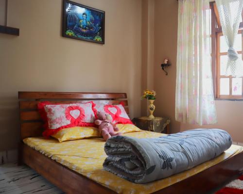 a bedroom with a bed with red and yellow pillows at Aama Homestay in Kurseong