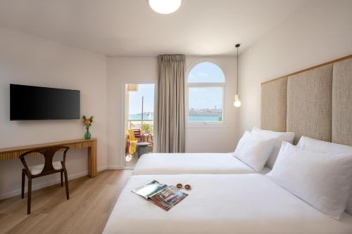 a hotel room with two beds and a tv at Naveh Tamar - Mehadrin Kosher suitable for Ultra-Orthodox guests in Acre