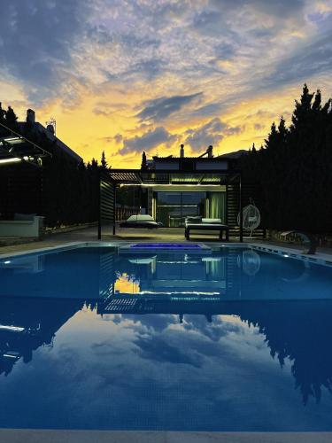 a house with a pool in front of it at Olivujoj Villajoj - Deluxe Villa with Detached Pool House in Anavyssos