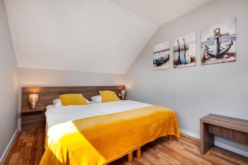 a bedroom with a large bed with yellow sheets at Corden Village in Łeba