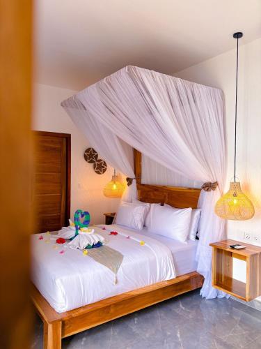 a bedroom with a white bed with a canopy at Ajolie Villa in Gili Islands