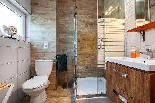a bathroom with a toilet and a shower and a sink at Corden Village in Łeba