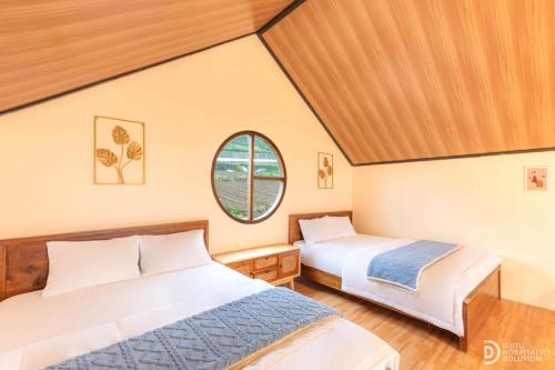 two beds in a room with a window at Umacabana 2 in Diyeng