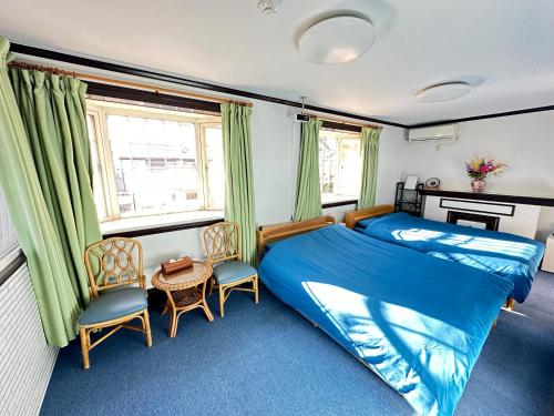 a bedroom with a bed and two chairs and a table at 自遊人の宿 in Odawara