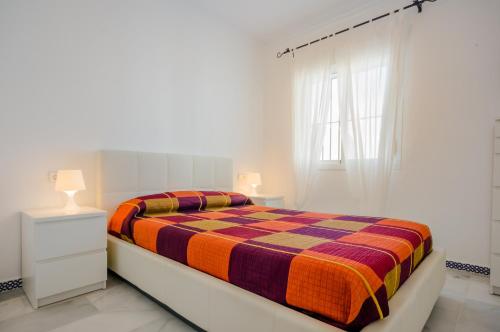 チクラナ・デ・ラ・フロンテーラにあるApartamento Babor Iの白いベッドルーム(カラフルな毛布付きのベッド付)