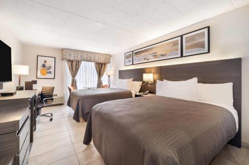 a hotel room with two beds and a television at Days Inn by Wyndham Sudbury & Conference Centre in Sudbury