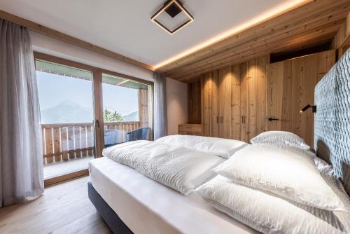 a bedroom with a bed with white pillows and a window at Chalet Esther in Longega