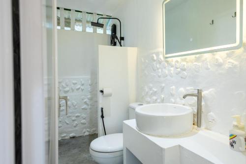 a white bathroom with a toilet and a sink at Coral Reef Holidays in Tioman Island