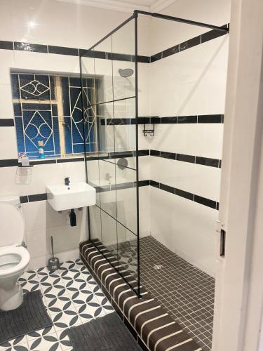a bathroom with a shower with a toilet and a sink at The Residence at 1907 in Thulamahashi