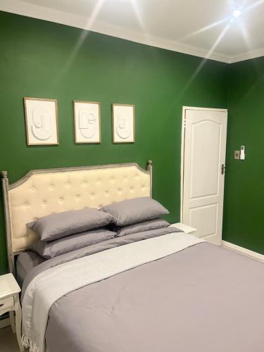 a bedroom with green walls and a large bed at The Residence at 1907 in Thulamahashi