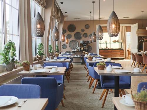 a restaurant with wooden tables and blue chairs at Strandhotel Miramar in Timmendorfer Strand