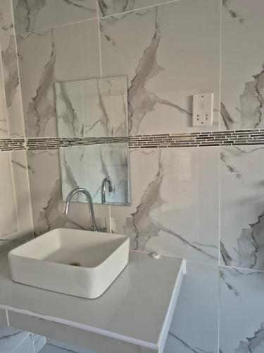 a white sink in a bathroom with marble walls at Paradise Reho Guesthouse in Nata