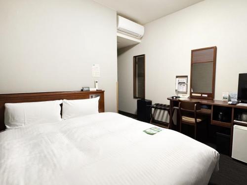 a bedroom with a bed and a desk with a computer at Hotel Route-Inn Isahaya Inter in Isahaya