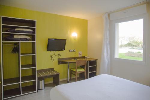 a room with a bed and a desk and a television at Auberge de la Baie in Ardevon