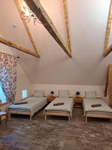 a room with four beds and a ceiling with beams at Stebuklėlis in Pakruojis