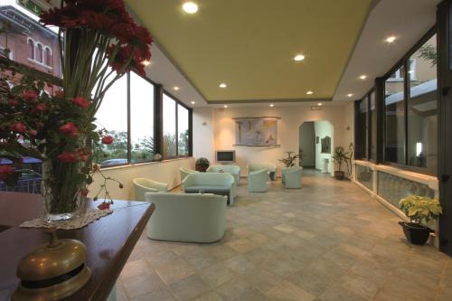 a lobby with a waiting room with couches and flowers at Hotel Flora in Cesenatico