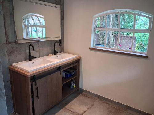 a bathroom with a sink and a mirror and a window at de Zeilende kraay in Katwijk