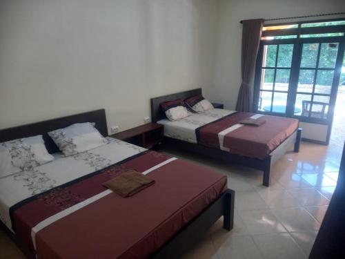a bedroom with two beds and a window at Popeye Karimunjawa in Karimunjawa