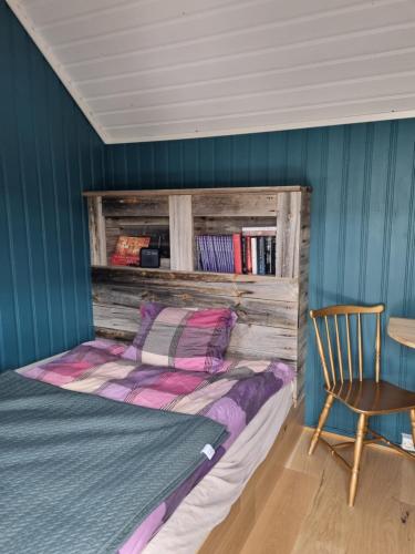 a bedroom with a bed and a chair and a table at Bjørneboestova in Åmli
