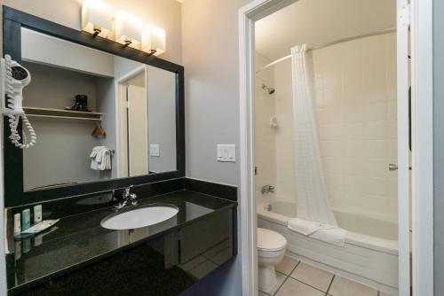 a bathroom with a sink and a toilet and a mirror at Quality Inn & Suites in Vernon
