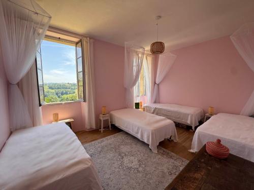 a bedroom with two beds and a large window at Le Couvent in Lunac