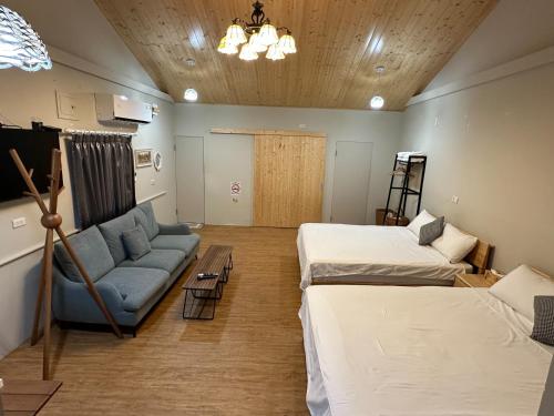 a room with two beds and a couch in it at 旅人路過時民宿 in Hsi-lo