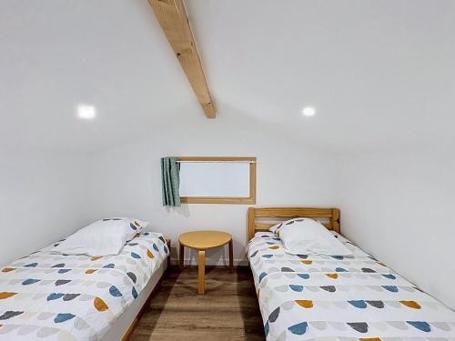 zwei Betten in einem Zimmer mit einem Tisch und einem Fenster in der Unterkunft Le Peage de Perouges in Pérouges