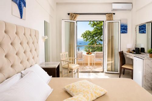 a bedroom with a bed and a view of the ocean at Cavomarina Beach- Adults Only in Kavos