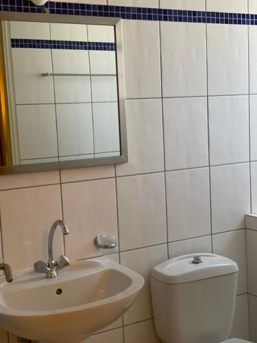 a bathroom with a sink and a toilet and a mirror at Hotel Karthea in Korissia